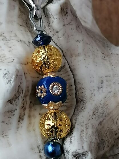 Schlüsselanhänger mit Einhorn mit schwarzweissem emaillierten Einhornanhänger goldenen Drahtperlen dunkelblauer Kashmiriperle mit silbernen und goldenen Ornamenten