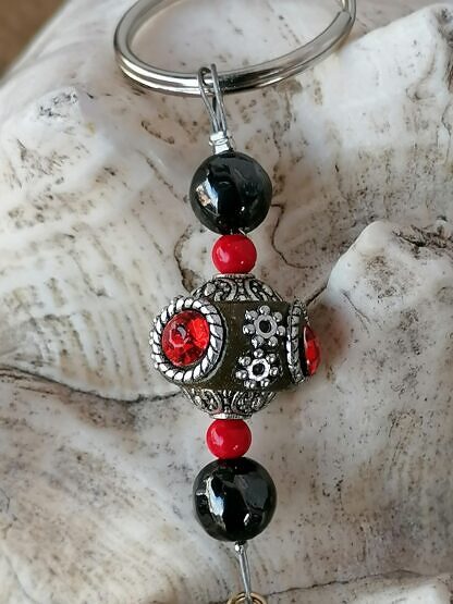 Schlüsselanhänger mit Einhorn mit rotweissem emaillierten Einhornanhänger dunkelbrauner Kashmiriperle roten Acrylperlen und schwarzen Glasperlen