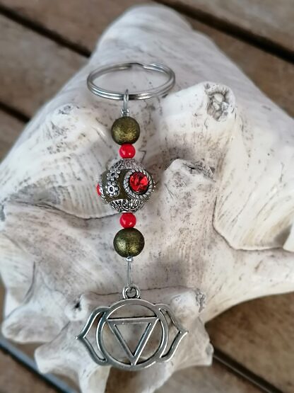 Yoga Schlüsselanhänger mit Kashmiri Perle lindgrün mit roten Strasssteinen olivgrünen Sternenstaubperlen roten Acrylperlen und Yoga Symbol Ajna Stirn Chakra