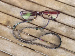 Brillenkette mit facettierten grünviolettgoldenen Glasperlen schwarzen und grauen Acrylperlen anthrazit Katzenaugenglasperlen schwarze Brillenschlaufe mit goldenen Karabiner