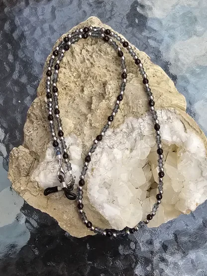 Brillenkette mit hellblauen facettierten Glasperlen silbernen Metallperlen schwarzen Acrylperlen schwarz-silberne Brillenschlaufe und silberne Karabiner