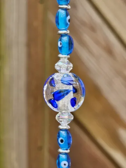 Schwemmholz Girlande Dekohänger Traumfänger Sonnenfänger mit dunkelblauen Pompons blauen Glasperlen Auge Fatimas diverse Formen von blauen Lampwork Perlen silberne Acryl Tibetperlen Perlkappen Metallperlen