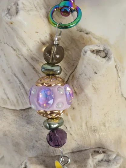 Schlüsselanhänger mit Einhorn mit weissem Anhänger mit gelb, blau und rosa Blumen Kashmiriperle in lila gold grüne Glanzperlen violette und hellbraune Glasperle